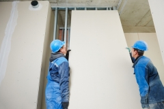 cheerful plasterboard workers team at a indoors wall insulation works