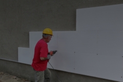 Worker drilling styrofoam sheet insulation on the wall
